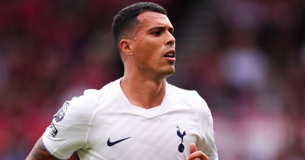 Spain footballer Pedro Porro playing for Premier League team Tottenham Hotspur Football Club in a white Spurs home shirt with the club badge and Nike tick in dark blue on the chest in a stadium looking to his left